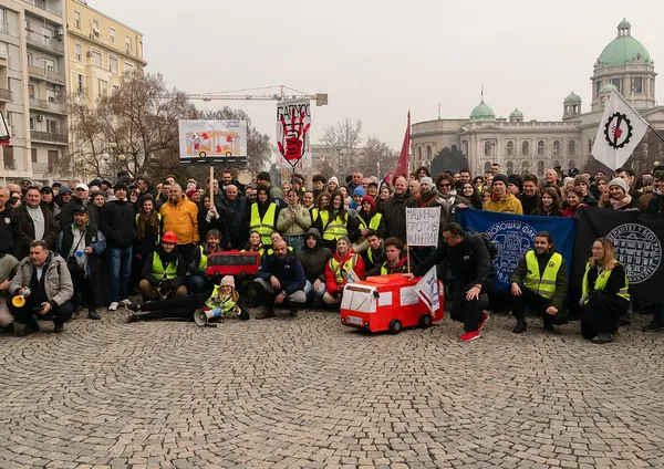 Велика групна фотографија студената на тргу испред Скупштине са макетом аутобуса